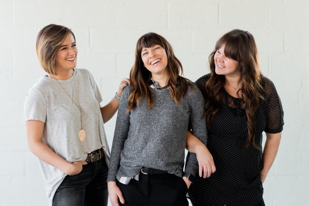 three white women standing and smiling 