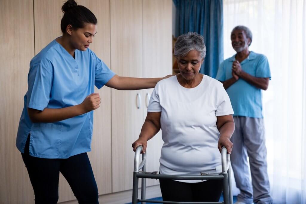 nurse helping older woman with a walker