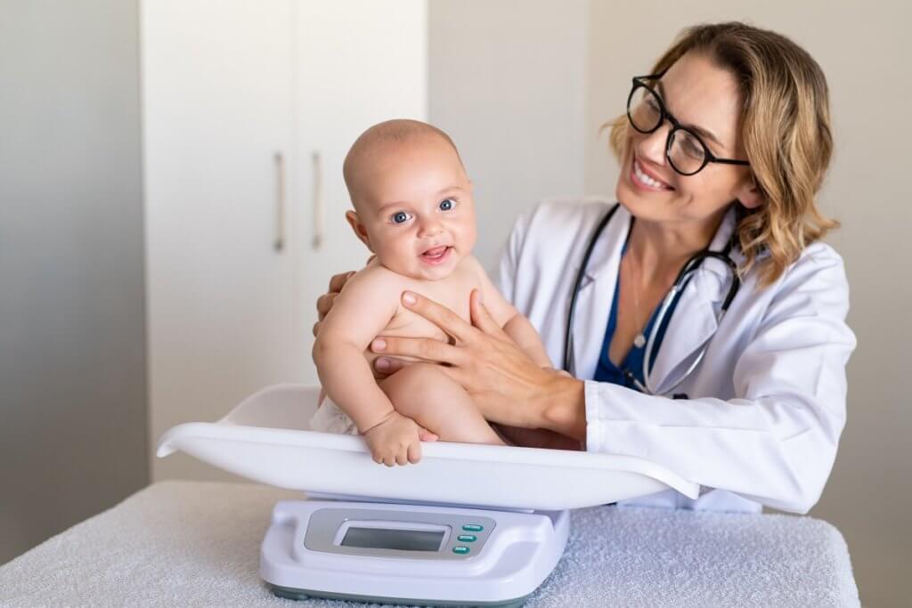 female doctor weighing a baby in doctor's office 