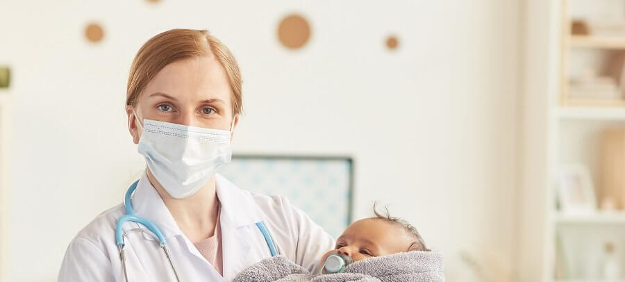 doctor in mask holding newborn baby