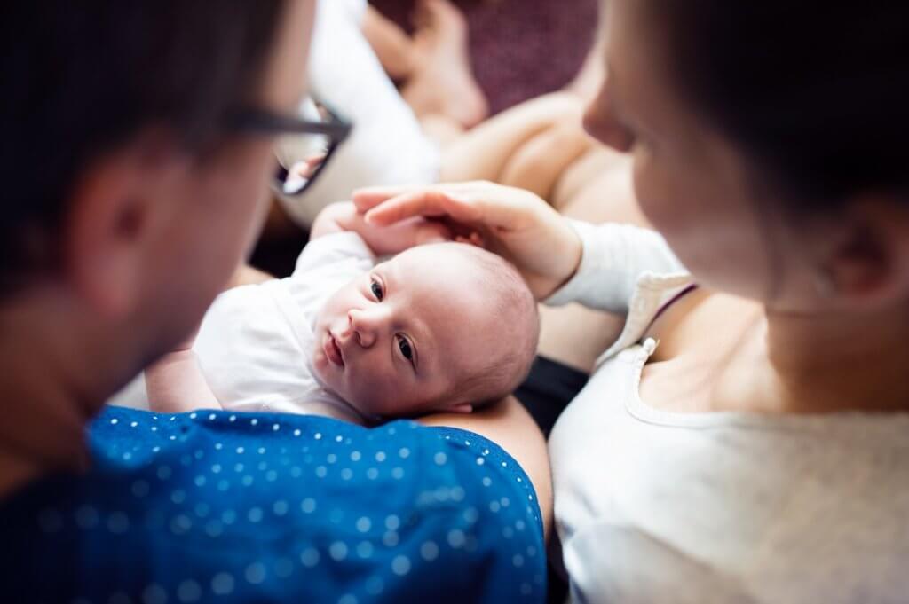 2 adults holding a young baby