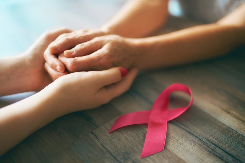 two women holding hands with pink ribbon