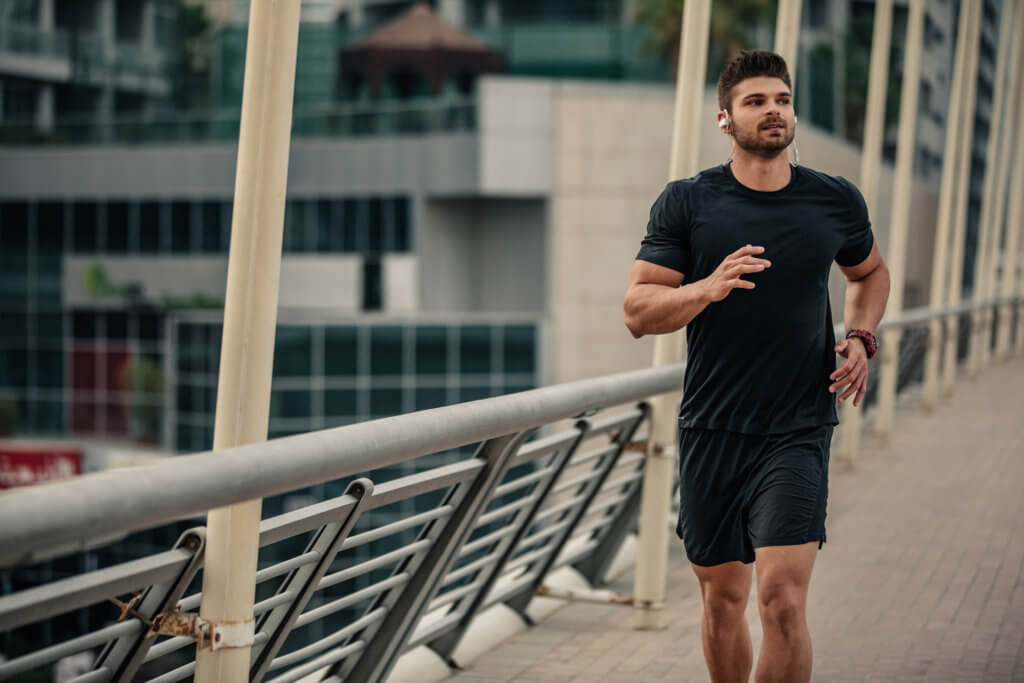 younger man running outside on a bridge