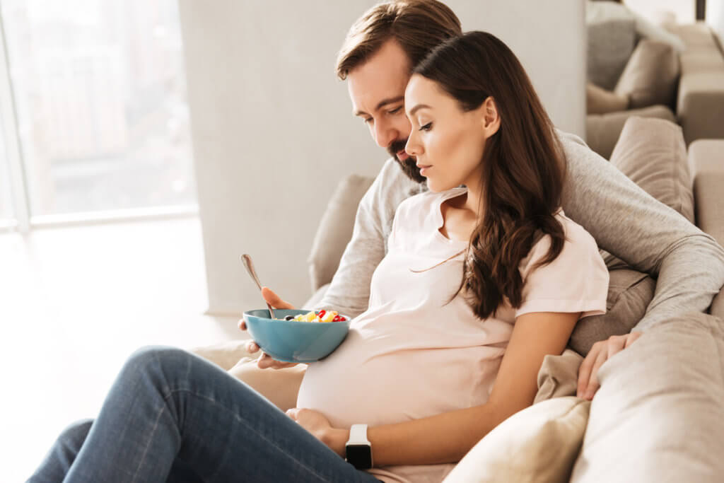 oung pregnant couple relaxing on a couch