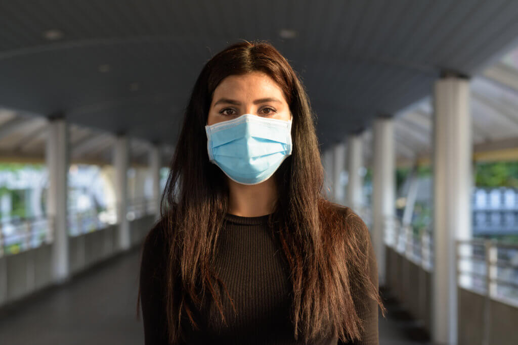 a young woman wearing a mask while standing outside