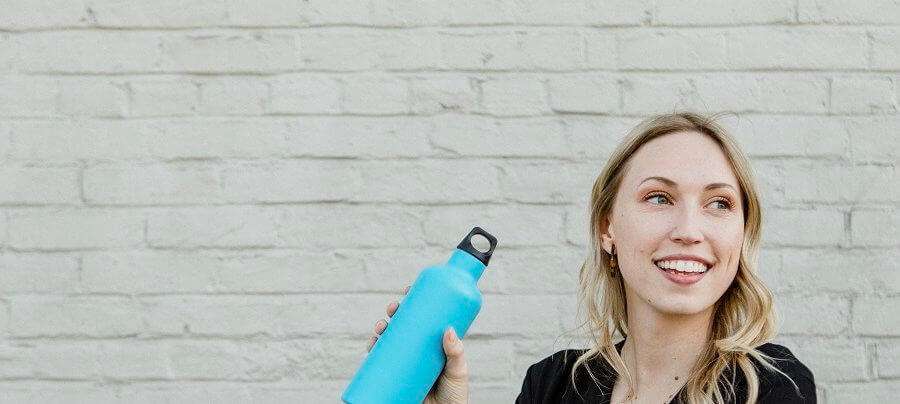 Happy woman carrying a thermal bottle