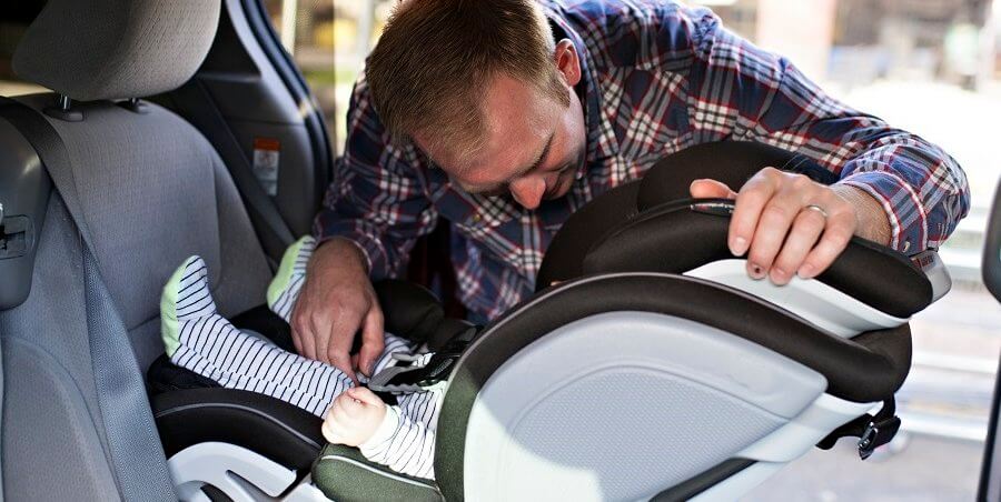 a man putting a baby in a car seat