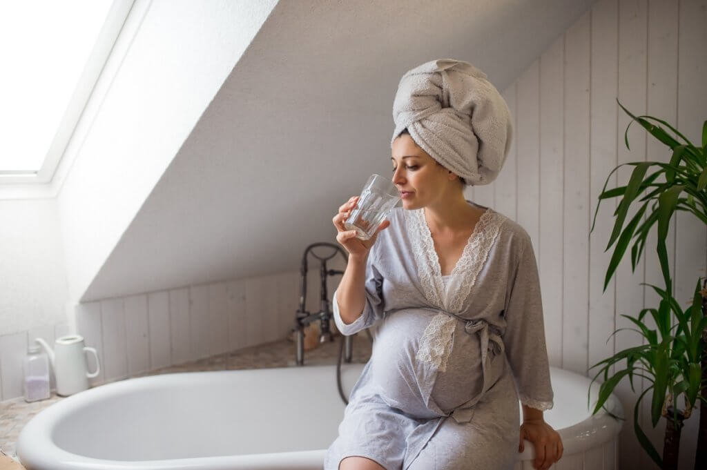 pregnant woman sitting on bathtub ledge