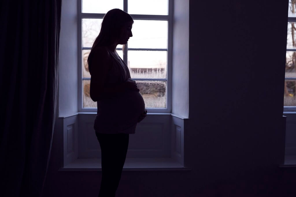 pregnant woman standing by window