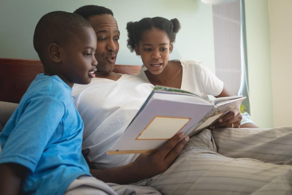 a father reading a bedtime story to 2 kids