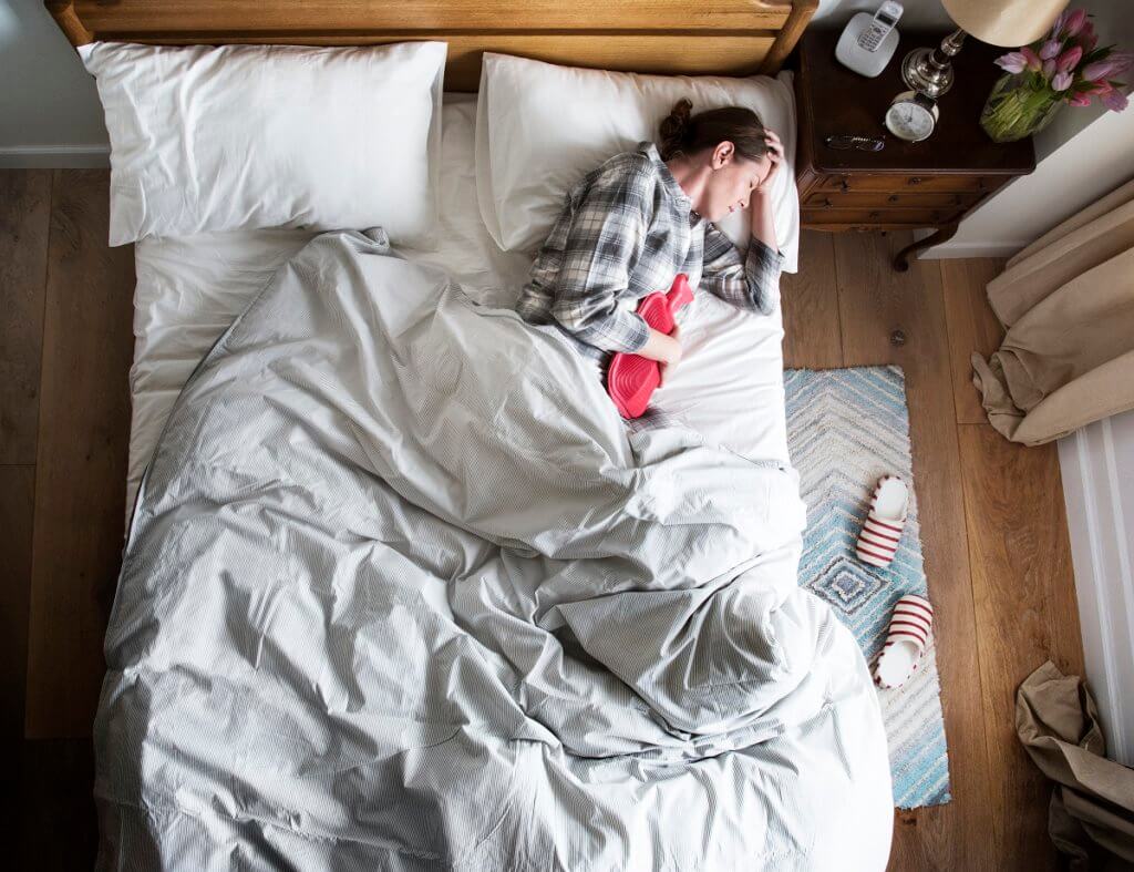 woman experiencing pain and lying in bed