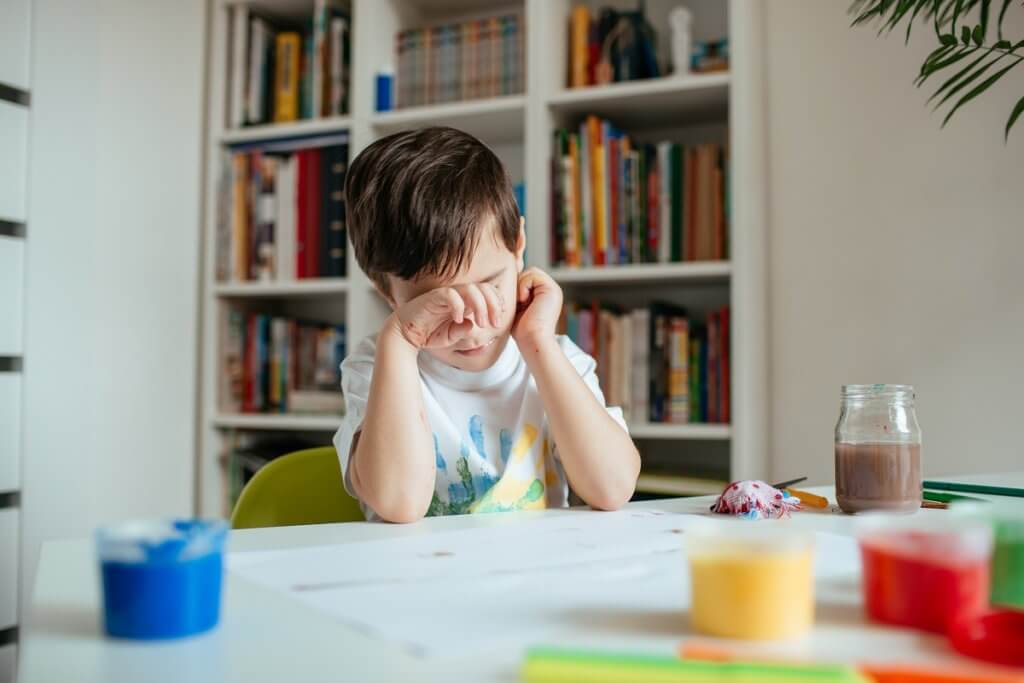 young boy rubbing eyes