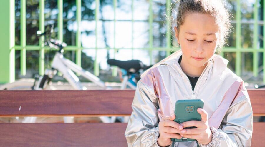 Teen girl using smartphone outdoors.