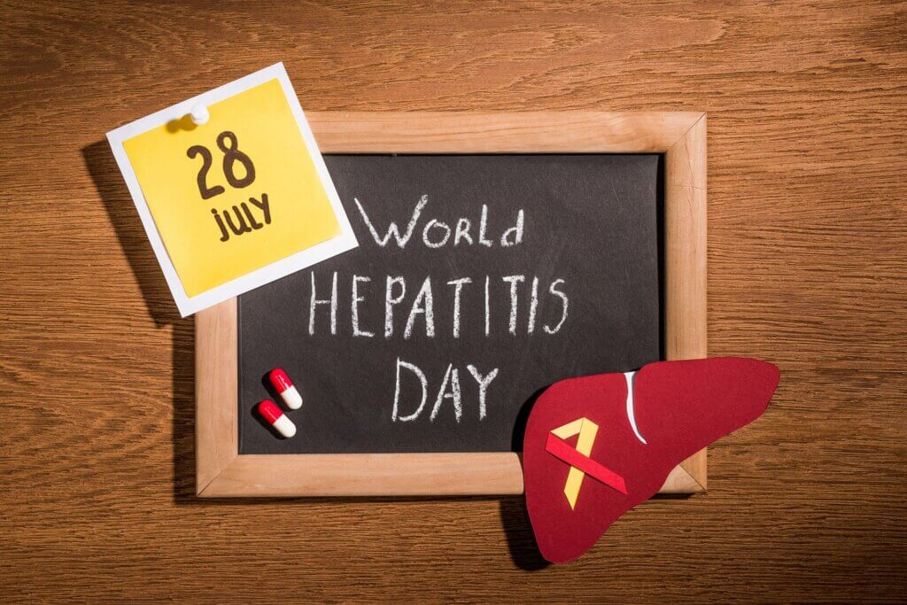 top view of blackboard with lettering world hepatitis day, liver, pills and stick it with lettering